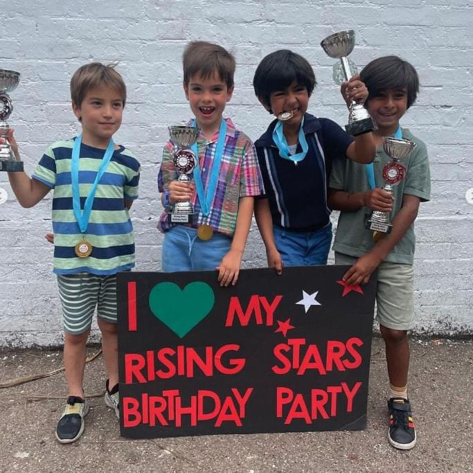 Four young boys posing with Rising Stars birthday party sign