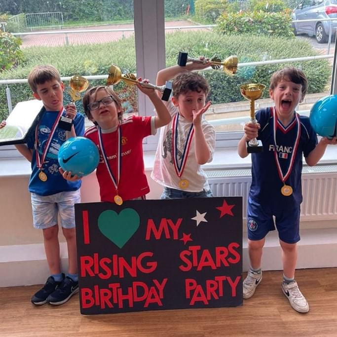 Four young boys posing with Rising Stars birthday party sign