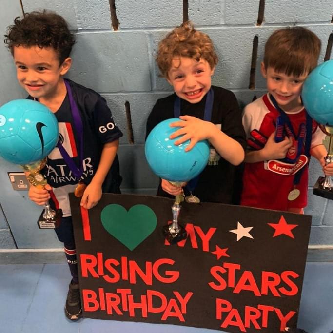 Three young boys posing with Rising Stars birthday party sign