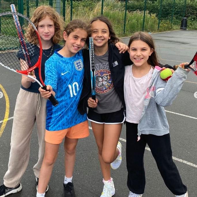 Four young girls with tennis racquets at a rising stars holiday camp