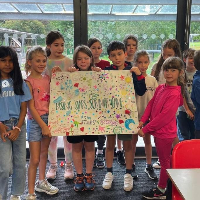 Bunch of children holding up a Rising Stars holiday camps sign