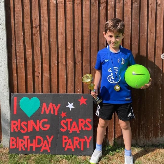 Young boy posing with Rising Stars birthday party sign