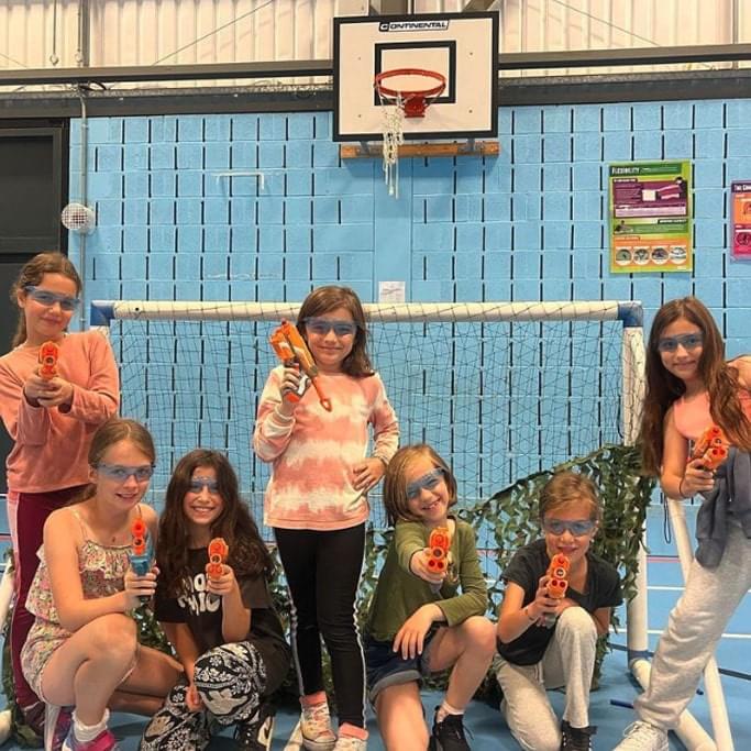 Seven young girls at a Rising Stars nerf gun birthday party