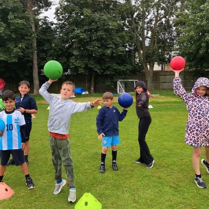 children playing with dodgeballs outdoors